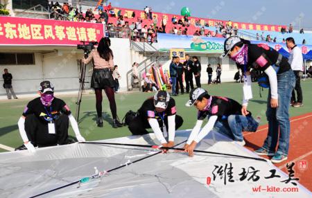 队员们合作将一只活动主题大风筝组装起来准备放飞